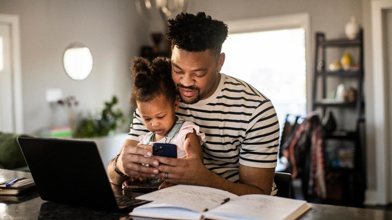 Dad works on computer with daughter on his lap