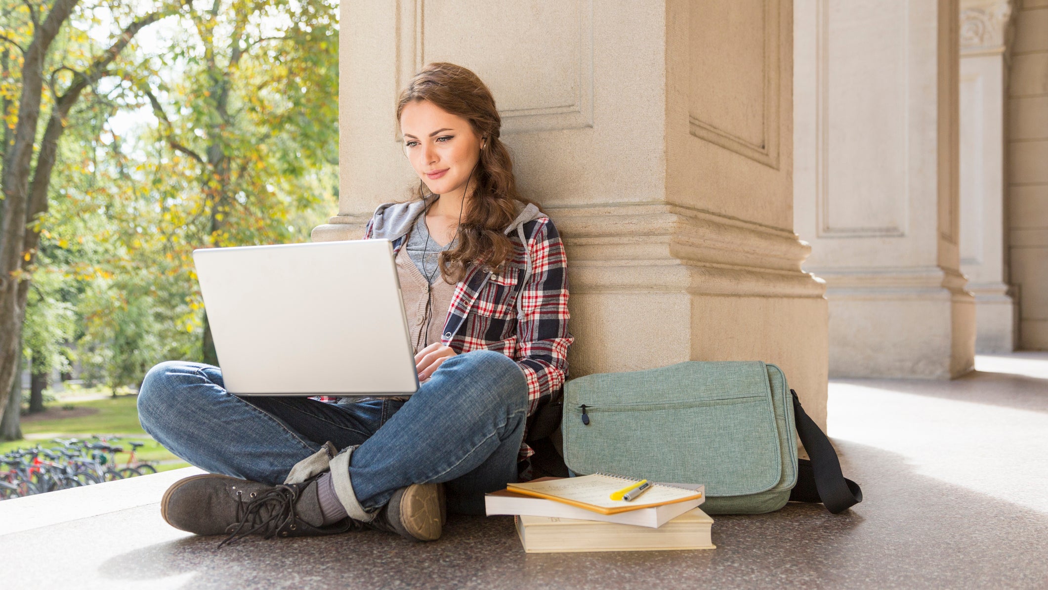 College student studying with laptop and earbuds