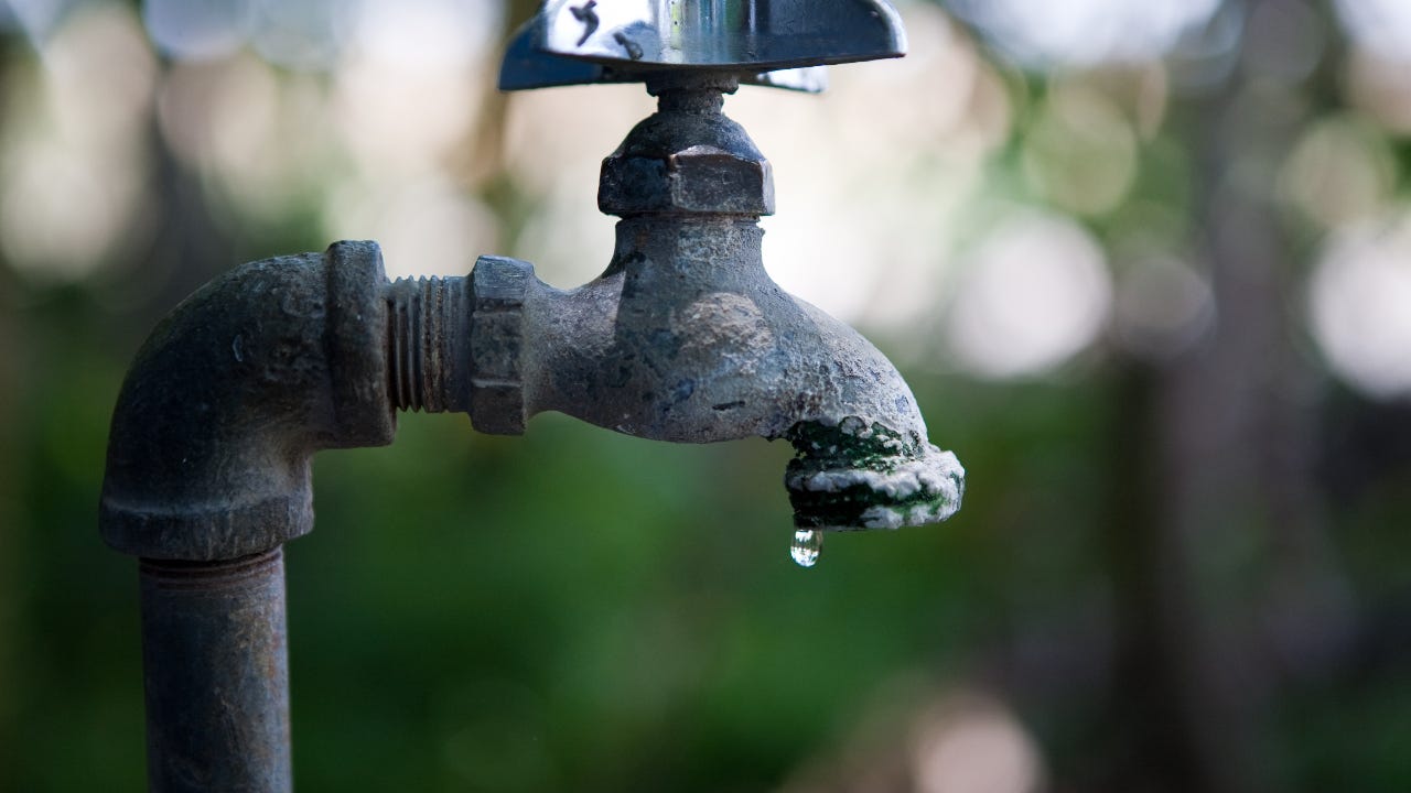 A water faucet leaks a drop of water