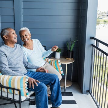 Two seniors enjoy sitting outside their home