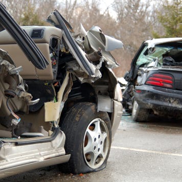 Two completely totaled cars including one with its rear window smashed in and the other missing the door on the passenger side.