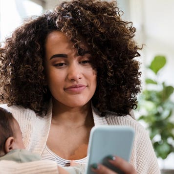A woman searches for mortgage rates on her phone with her child in tow