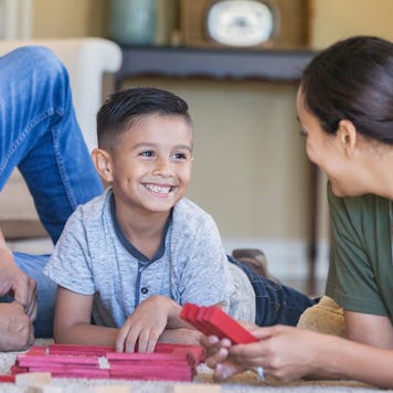 A boy plays with blocks with his parents; his mother is in the military