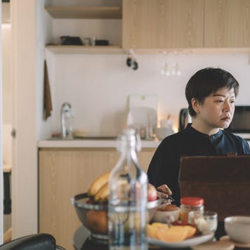 an asian chinese mid adult woman working from home at dining table using digital tablet and documents during breakfast time