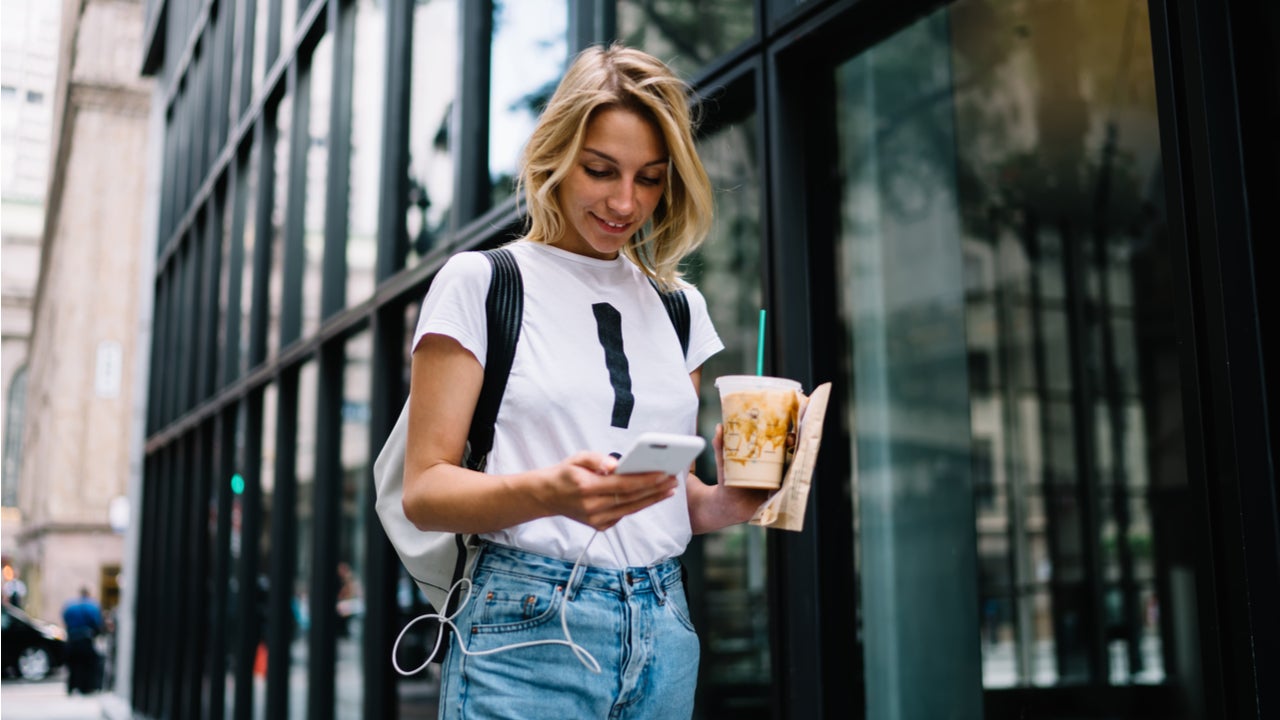 Student walks down the street looking at her phone.