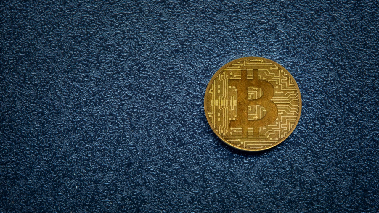 A physical representation of a bitcoin on a blue background