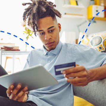 man looking at credit card and digital tablet