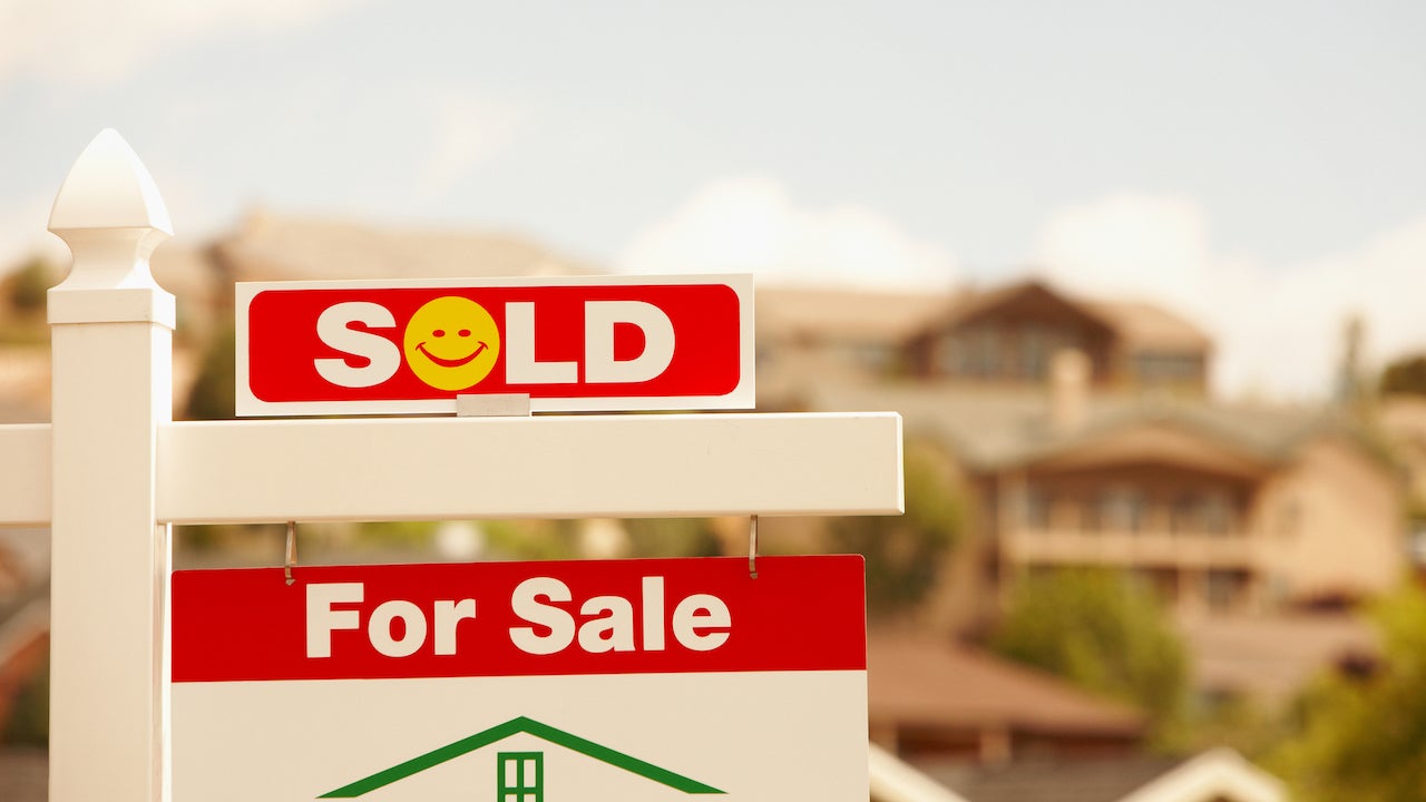 how to sell your house fast - red and white "sold" sign with yellow smiley face in front of suburban house