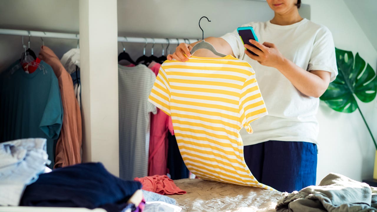 person taking cell phone photo of a shirt from the closet