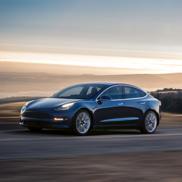 A blue 2022 Tesla Model 3 driving down the highway