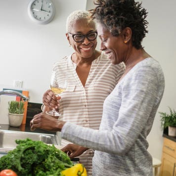 Two smiling Black women cook together.