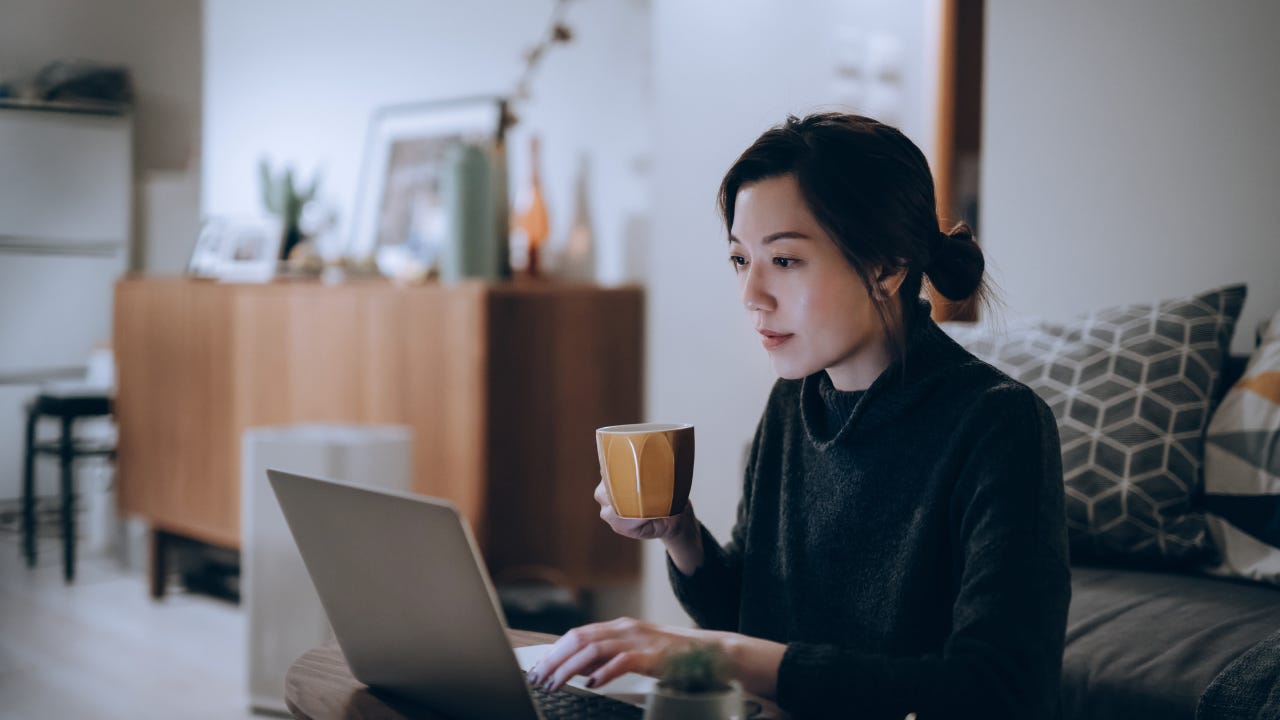 Busy concentrated young woman working from home, working on laptop till late in the evening at home.
