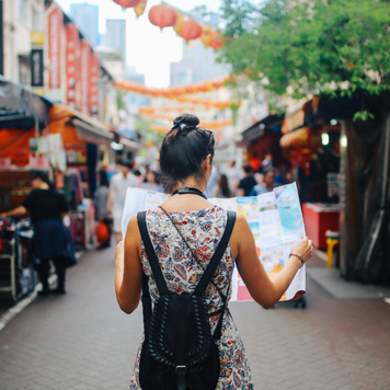 Solo woman traveler on street holding a map