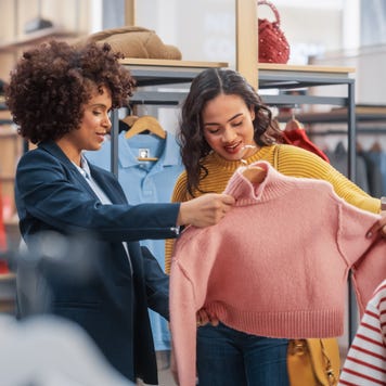 Young Female Customer Shopping in Clothing Store, Retail Sales Associate Helps with Advice. Diverse People in Fashionable Shop, Choosing Stylish Clothes, Colorful Brand with Sustainable Designs