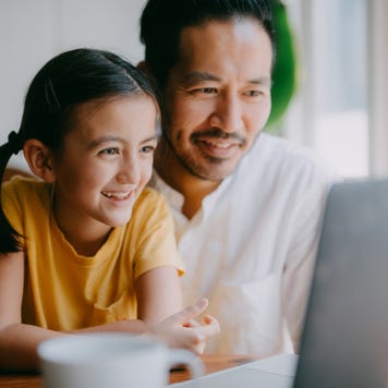 Happy father and young daughter on laptop video call at home, Tokyo