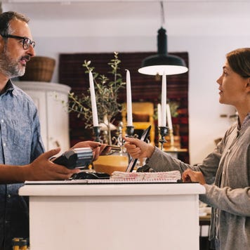 Owner giving credit card to female customer while standing at shop counter