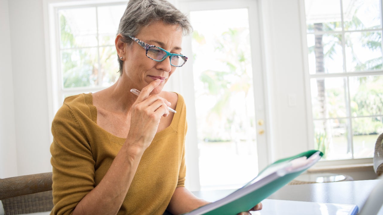 Woman reading folder at desk in living room