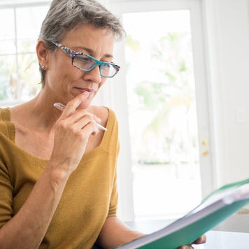 Woman reading folder at desk in living room