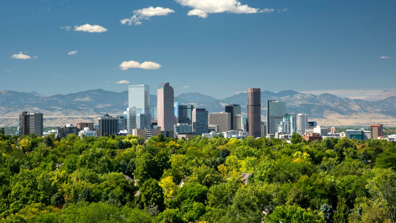 The towering high rises of Denver's downtown sit between the Front Range of the Rocky Mountains to the west and the tree lined neighborhoods and parks of the city to the east.