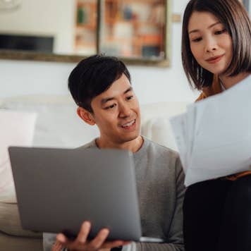 Young couple discussing over financial bills while using laptop on sofa
