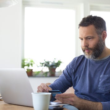 Businessman paying through credit card on laptop at home