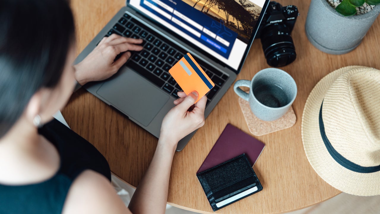 High angle view of young woman booking flight tickets online using laptop