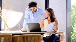 A couple looks at a laptop computer and documents while working on their investments.