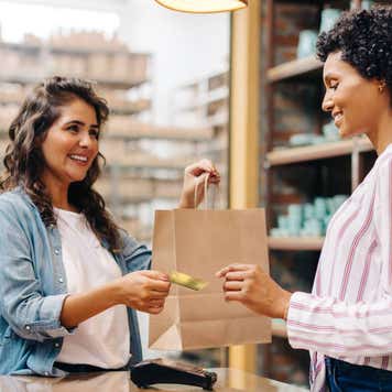 Happy young shop owner receiving a credit card from a customer