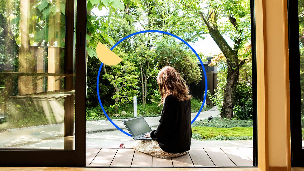 A woman sitting on a porch looking at a laptop