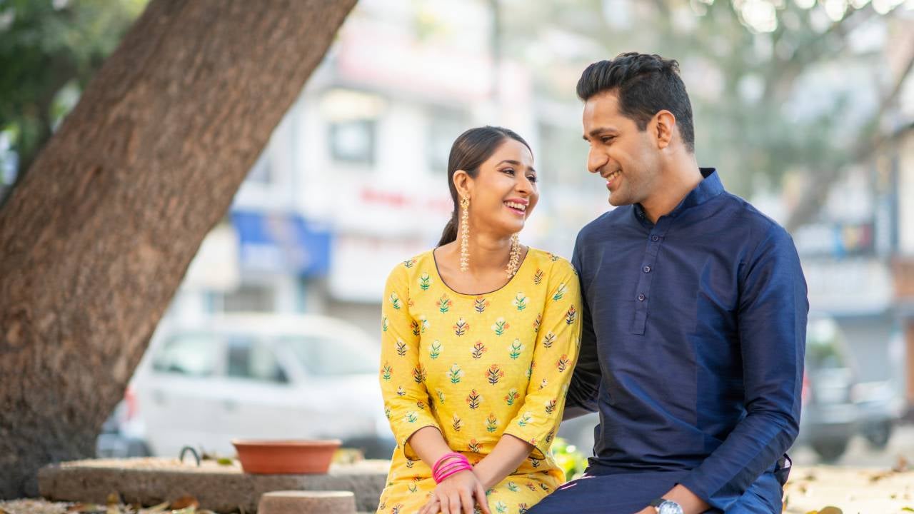 An Indian couple sits side by side while looking at each other lovingly.
