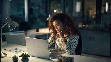 Shot of a young businesswoman using a laptop during a late night at work