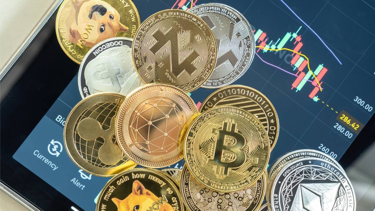 Various crypto tokens on top of a tablet displaying a price chart.