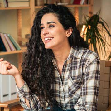Portrait of a happy young woman using credit a card for online shopping at home