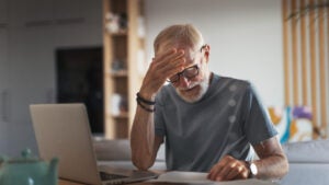 An elderly white man with an anxious expression reviews paperwork.