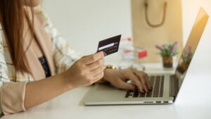 Hands at a laptop with a credit card.