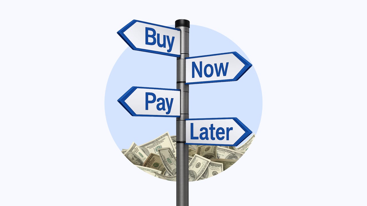 A signpost that reads "buy now pay later" with a pile of money behind it.