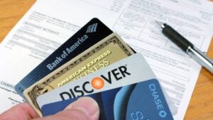 Four real credit and debit cards with a credit cards statement on a desk in the background.