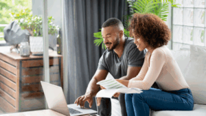 A couple sitting at home working on their finances on their laptop.