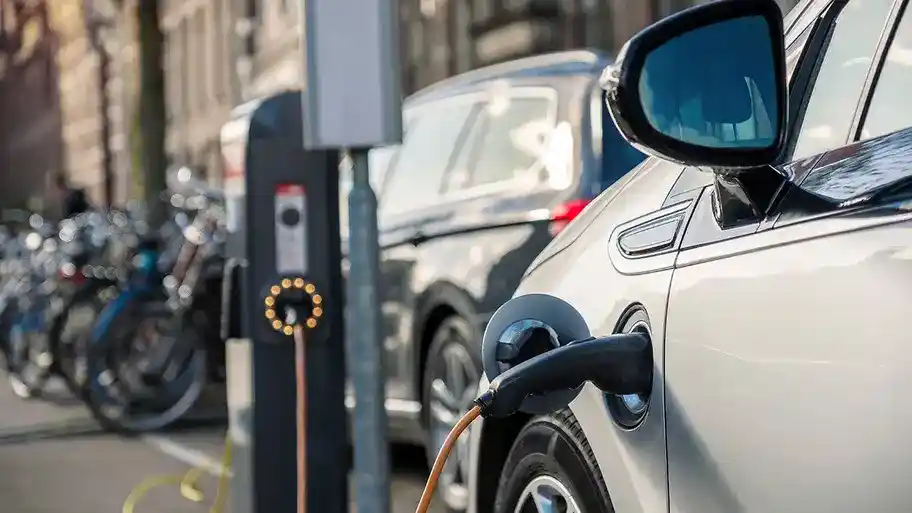 Electric vehicle charging: An EV plugged into a charging station, with the charging cable connected to the vehicle's charging port.