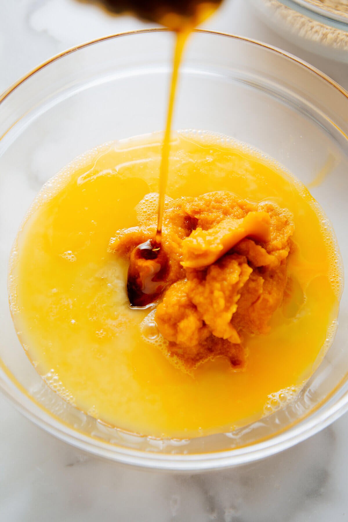 pouring maple syrup into pumpkin batter